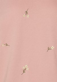 Tessuto rosa con piccoli fiori ricamati bianchi e steli verdi distribuiti uniformemente sulla superficie.