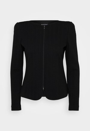 Black textured zip-up jacket with long sleeves, featuring a round neckline and hem detailing, made from a ribbed fabric that adds depth.