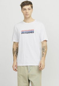 Witte katoenen t-shirt met een multicolore "JACK & JONES" logo op de borst in rood, blauw en zwart. Relaxte pasvorm met korte mouwen.