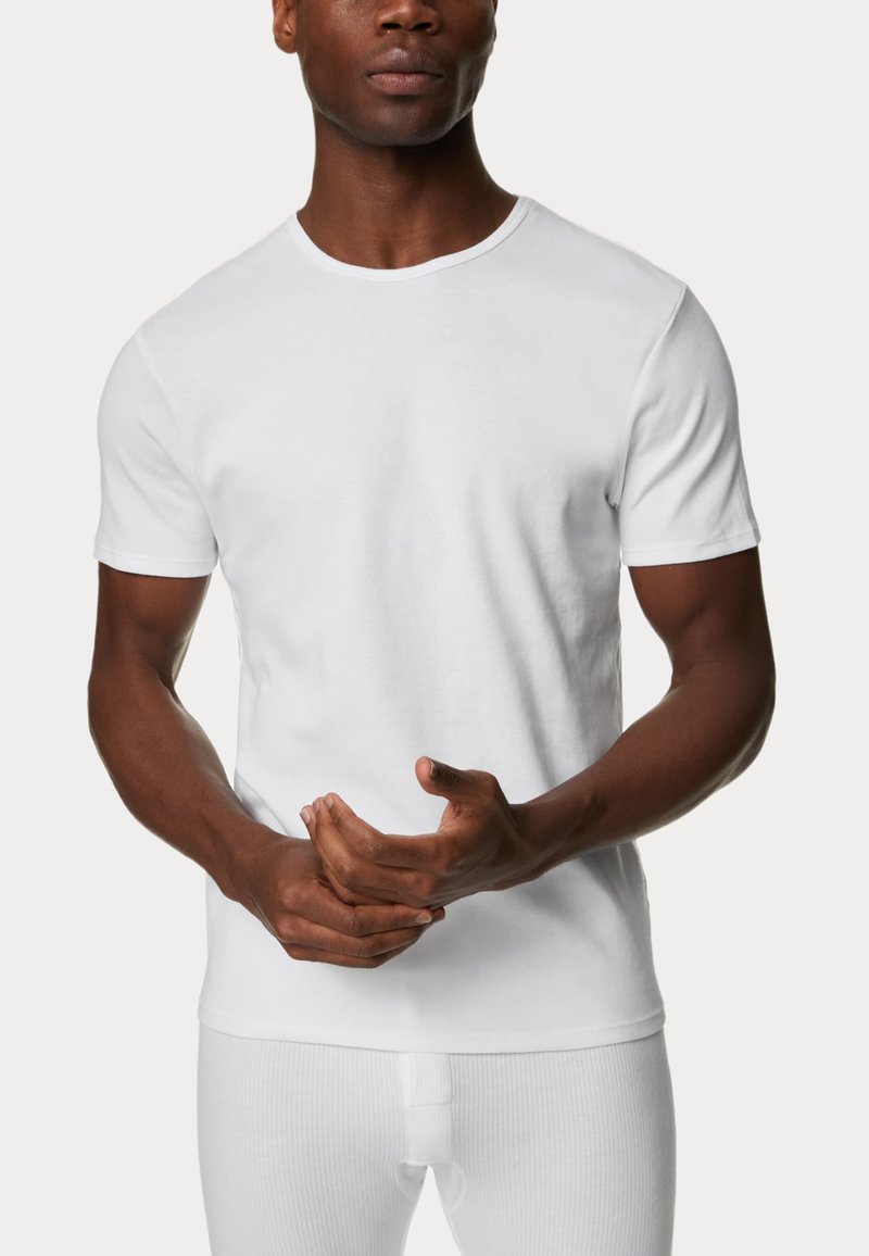 Camiseta blanca de manga corta hecha de algodón con cuello redondo. Textura suave, diseño ajustado, con un corte simple y clásico.