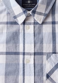 Blå och vit rutig skjorta med knapp-ner krage, med en bröstficka och texturerat tyg. Knapparna är vita med kontrasterande mönster.