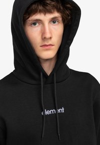 Sudadera negra de algodón, con un logo frontal que dice "element" en blanco. Incluye capucha con cordón y una textura suave.