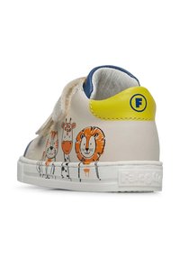 Witte leren schoen met blauwe en gele accenten. Heeft speelse dierenillustraties aan de zijkant. Klittenbandsluiting voor eenvoudig aan- en uittrekken.