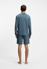 Sininen, teksturoitu pitkähihainen paita ja siihen sopivat shortsit, molemmat kevyestä kankaasta, esitettynä takaa rentona mallina.