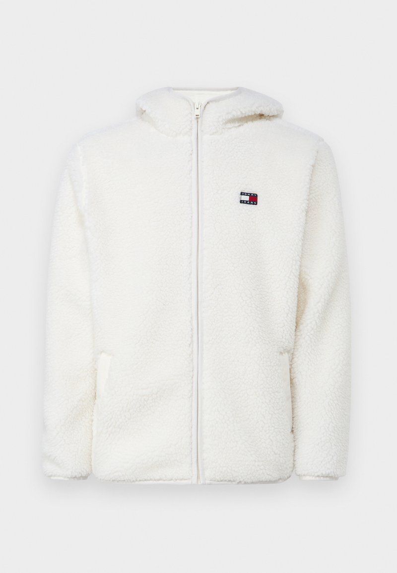 Sweat à capuche zippé en polaire blanche avec une texture douce, doté d'une capuche et de poches latérales. Petit logo sur la poitrine gauche. Fermeture éclair lisse.