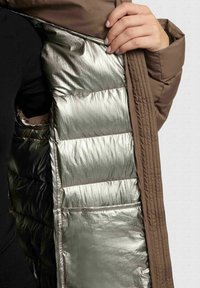 Brown puffer jacket with a metallic silver lining; features quilted texture, vertical panels, and a smooth outer fabric.