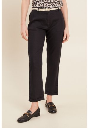 Pantalons en lin noir au fit ajusté, avec des ourlets roulés et une ceinture tissée. Associés à des mocassins noirs avec des accents en matériel doré.