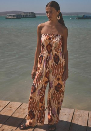 Bunt gemusterter Jumpsuit im trägerlosen Design mit tailliertem Bund und weitem Bein. Hergestellt aus leichtem Stoff.