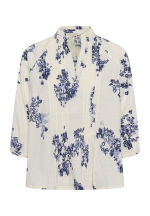 Blouse blanche à manches 3/4, imprimé floral bleu, tissu à pois texturé, et col court montant avec une ouverture en V.