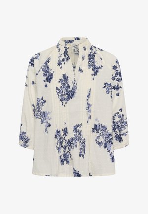 Blouse blanche à manches 3/4, imprimé floral bleu, tissu à pois texturé, et col court montant avec une ouverture en V.