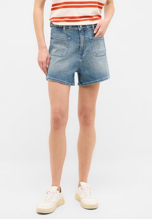 Pantalones cortos de denim en azul claro con un corte clásico, que cuentan con dos bolsillos traseros y dobladillo cosido. Combinados con zapatillas blancas y una camiseta de rayas.