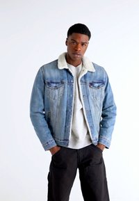 Veste en jean bleu clair avec un col en fausse fourrure crème doux. Dotée d'une fermeture à boutons à l'avant, de poches poitrine et d'une coupe décontractée.