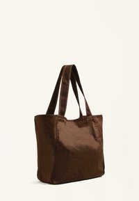 Brown tote bag made of textured fabric, featuring two sturdy handles and a spacious, rectangular design without visible hardware or accents.