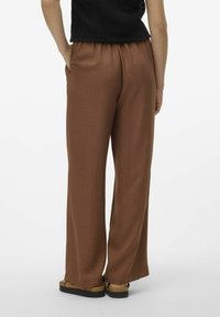Pantalons larges marron en tissu texturé avec une taille élastique et des poches latérales, assortis à des sandales.