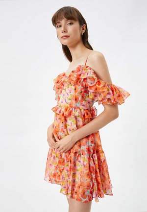Bloemenjurk met gerimpelde schouderloze mouwen, levendige oranje en roze tinten, lichtgewicht stof en een uitlopende rok met gelaagde tiers.