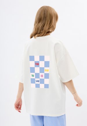 Witte oversized t-shirt met een pastelgevlekte afbeelding op de achterkant met de tekst: "TOO RAD TO BE SAD" in verschillende kleuren.