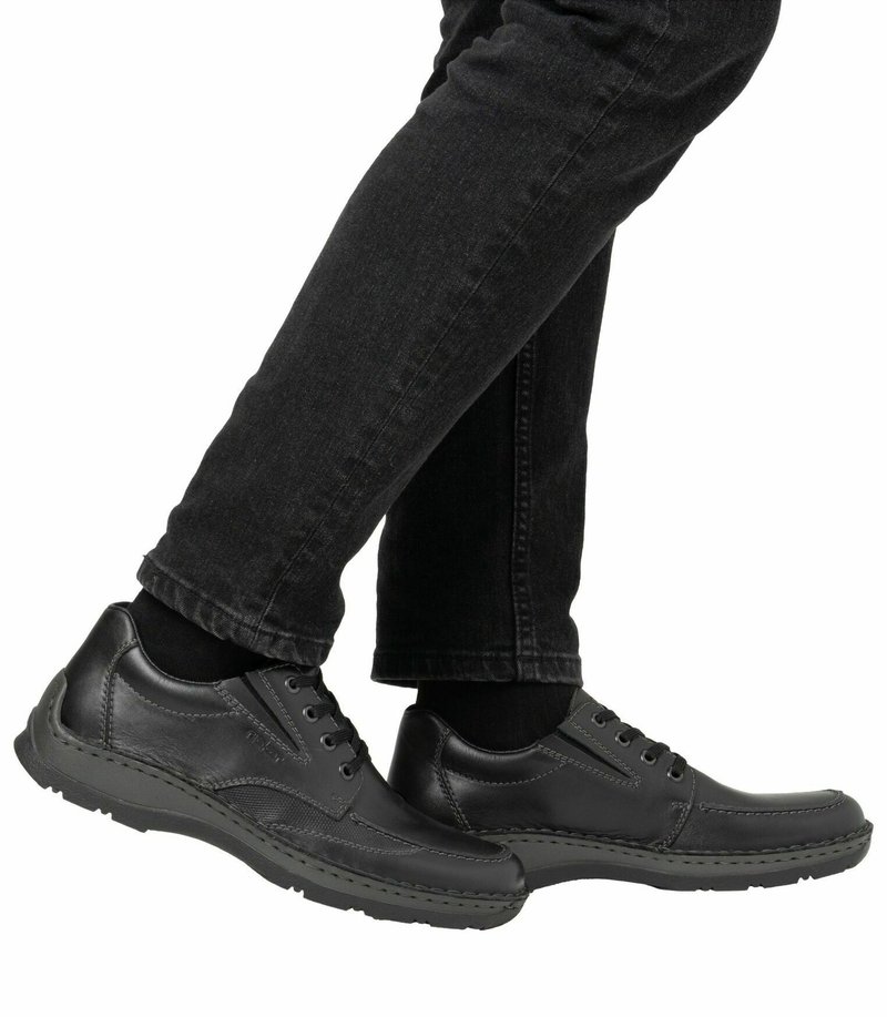 Chaussures en cuir noir avec un design à lacets, bout rond, couture contrastante et semelle en caoutchouc. Portées avec un pantalon en denim noir.