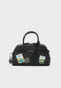 Brązowa torebka Karl Lagerfeld z czarnymi rączkami, ozdobiona naklejkami podróżnymi z Paryża i Monako oraz małą dołączoną czarną metką.