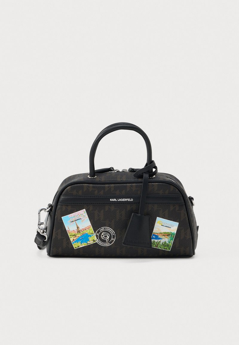 Brązowa torebka Karl Lagerfeld z czarnymi rączkami, ozdobiona naklejkami podróżnymi z Paryża i Monako oraz małą dołączoną czarną metką.