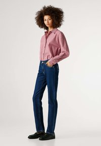 Κόκκινο και άσπρο ριγέ πουκάμισο με κουμπιά, μπλε τζιν τζιν, μαύρα παπούτσια· άνετη εφαρμογή, μακριά μανίκια και κλασικός σχεδιασμός με πέντε τσέπες.