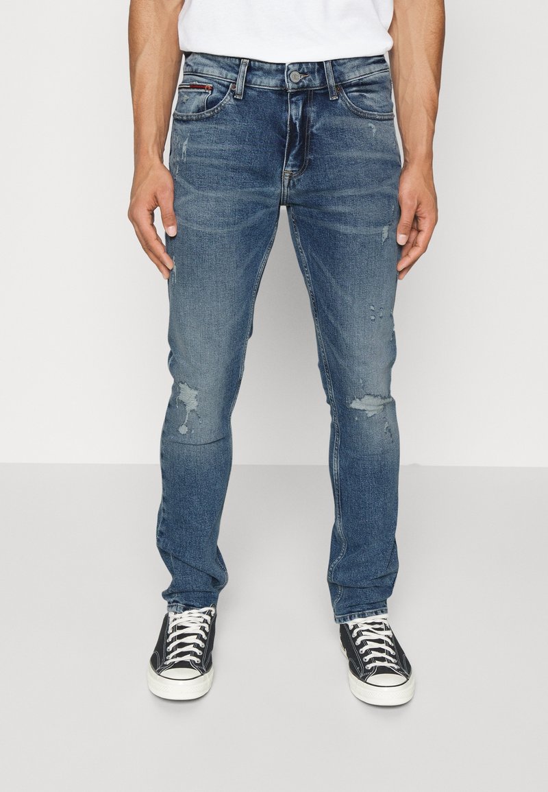 Blå denimjeans med slim fit, med lätt slitningar, framfickor och knäppning. Bärs med svarta högskor.