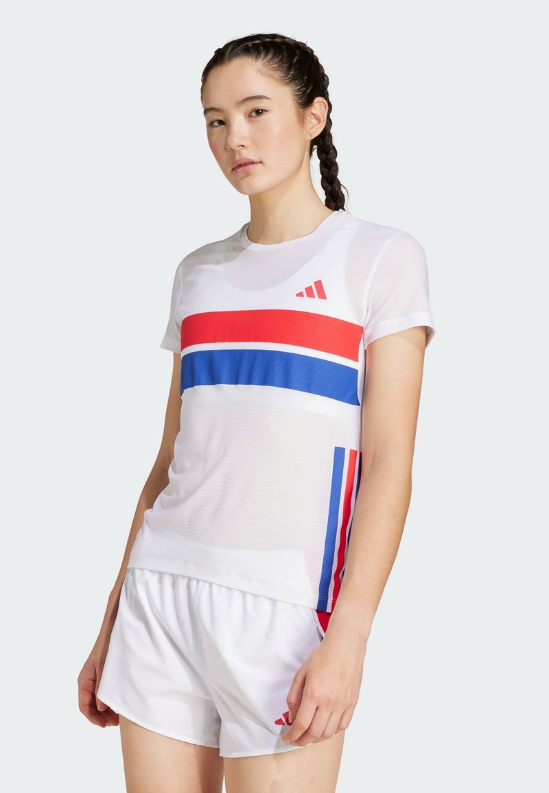 Balta sportinė marškinė su raudonais ir mėlynais horizontaliais raižiniais, trumpomis rankovėmis ir raudona Adidas logotipu. Derinama su baltomis šortais. Lygus paviršius.