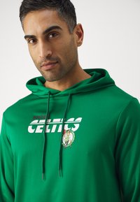 Žalia kapučino su Bostono Celtics logotipu baltos ir žalios spalvos. Medžiaga atrodo minkšta, su raišteliu kapučine ir priekinėmis grafikomis.