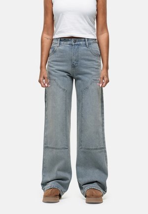 Lichtblauwe, wijde spijkerbroek van denim met grote opgestikte zakken, een hoge taille en een vervaagde afwerking. Gemaakt met bruine schoenen.