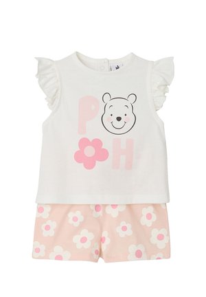 Weißes ärmelloses Oberteil mit gerafften Schultern, lächelndem Bärengesicht, pinkfarbenen Buchstaben und Blume, kombiniert mit pinkfarbenen Shorts, bedeckt mit weißen und pinkfarbenen Blumen.