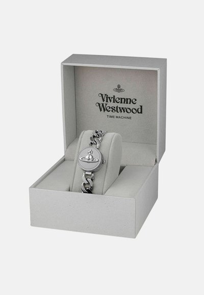 Montre en métal argenté avec un cadran rond, un bracelet à maillons, et un design de logo, présentée dans une boîte grise avec un intérieur doux.