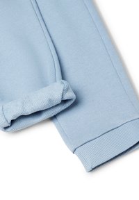 Světle modré bavlněné tepláky s texturovanými manžetami a vroubkovaným pasem. Mají hladký povrch a šňůrku v pase.