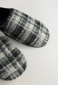 Gray and black checkered slippers with a soft, textured wool exterior and black inner lining. Rounded toe and flat soles.