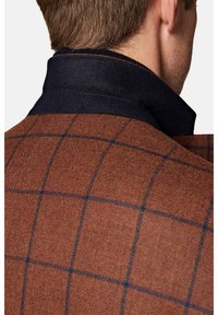 Brązowa marynarka w kratę z teksturowanej mieszanki wełny, z niebieskimi akcentami i jednolitą granatową kołnierzykiem, prezentująca nowoczesne detale krawieckie.