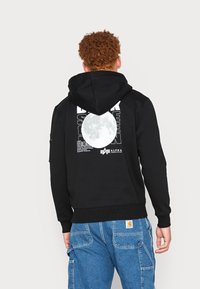 Sudadera negra con un gran gráfico de luna blanca y un diseño de texto en la parte posterior. Cuenta con una capucha con cordón y puños acanalados.