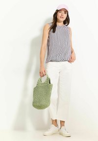 Haut sans manches rayé en gris et blanc, assorti à un pantalon large blanc et un sac tissé vert texturé, complété par des baskets blanches.