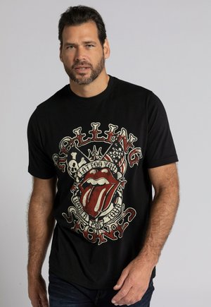 Sort t-shirt med en slidt grafisk tryk af Rolling Stones-logoet i rød og hvid, med yderligere designelementer som kranier og stjerner.