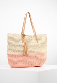 Vävd halm tote-väska med en beige övre del och en korallrosa botten. Har två tan läderremmar och en tofsaccent.