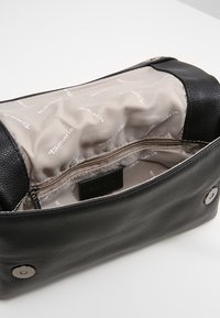 Černá kožená kabelka s hladkou texturou, uvnitř béžová podšívka s potiskem značky, kapsa na zip a zapínání na knoflík.