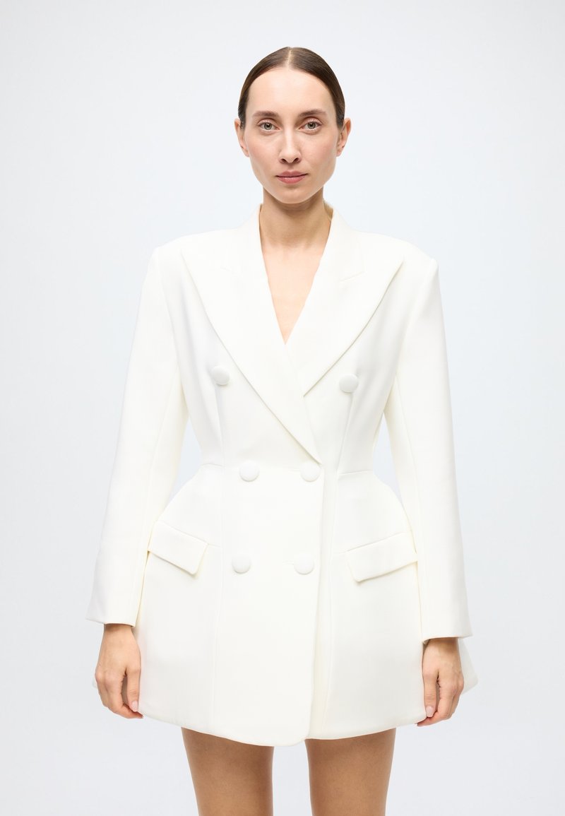 White double-breasted blazer with long sleeves, structured shoulders, and two front pockets, featuring round buttons and a smooth texture.