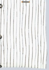 Weißer Stoff mit dünnen, vertikalen grauen Streifen. Beinhaltet runde schwarze Knöpfe und ein kleines graues Etikett mit orangefarbenen Akzenten.