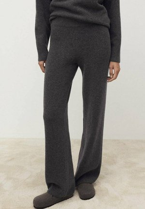 Gray knitted loungewear pants with a relaxed fit, soft texture, and wide legs. Paired with gray slippers on a light beige surface.