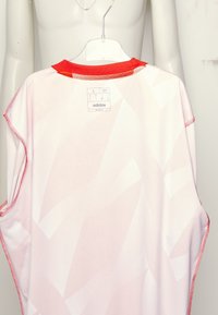 Camisa slim fit de Adidas en tejido suave y ligero; color rosa con patrones abstractos en blanco; cuello rojo y detalles de costura; lavable a máquina.
