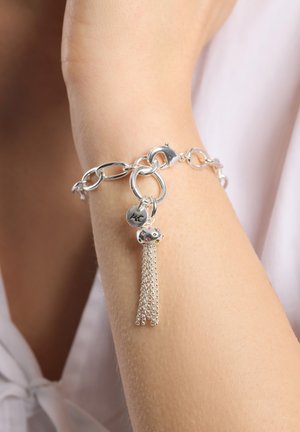 Silberne Kettenarmband mit großen Gliedern, einem Anhänger mit bunten Akzenten und einem Quasten aus feinen Kettengliedern.