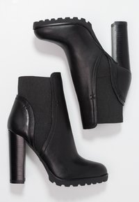 Bottines noires avec une tige en cuir lisse, des panneaux latéraux en élasthanne texturé et un talon épais haut avec une semelle striée.