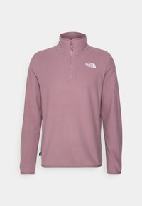 Lyslilla fleece pullover med halv lynlås krave, lange ærmer og et hvidt logo på venstre bryst. Glat tekstur og afslappet design.