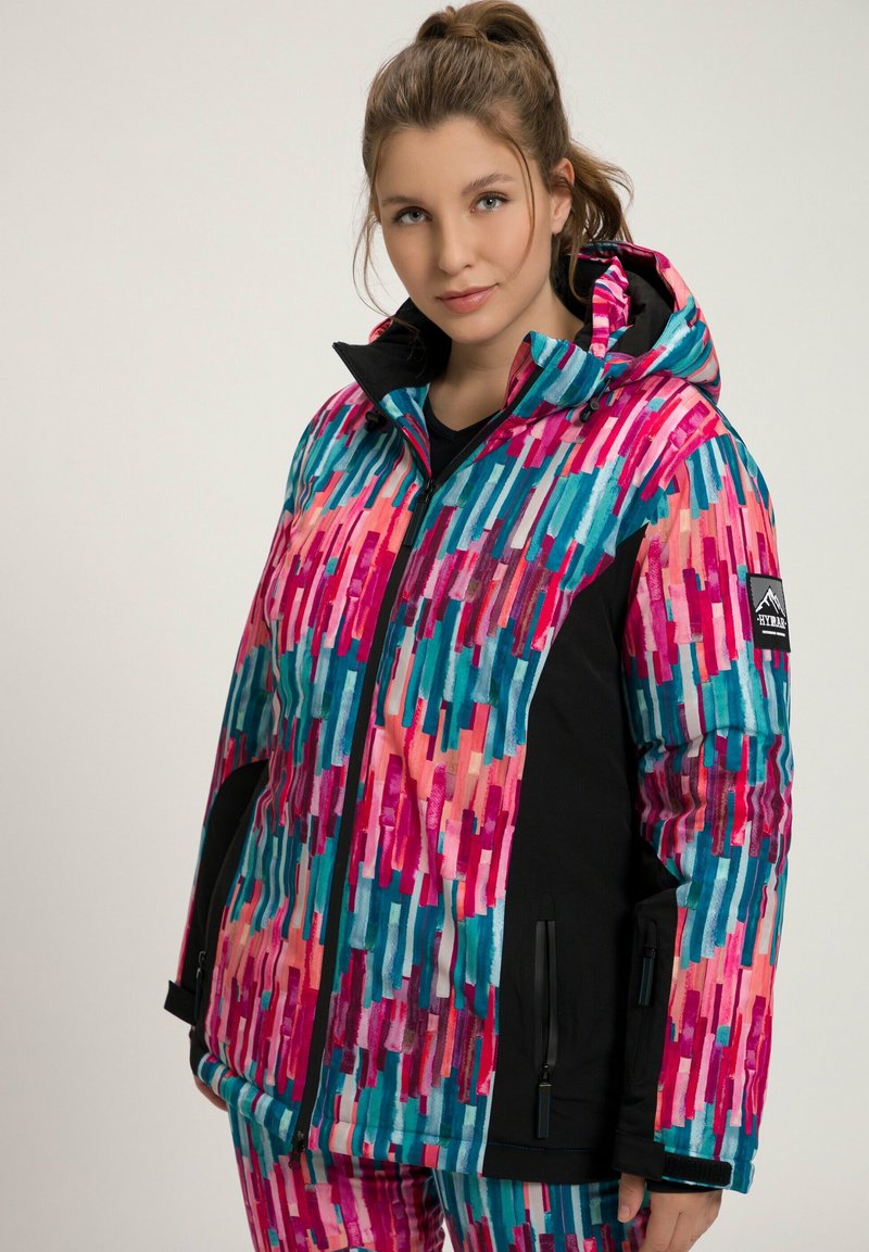 Giacca isolante colorata con un pattern geometrico in rosa, turchese e nero, dotata di cappuccio e tasche con zip. Accenti neri sulle maniche.