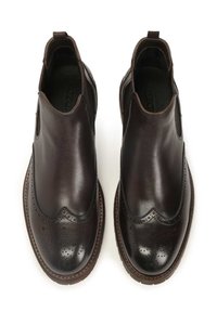 Stivali Chelsea in pelle marrone con dettagli brogue, texture liscia, pannelli laterali elastici e suola cucita. Design classico, stile funzionale.