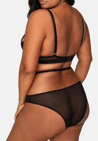 Czarny komplet bielizny, w skład którego wchodzi przezroczysty stanik z regulowanymi ramiączkami i zapięciem na haftkę, w połączeniu z pasującymi przezroczystymi majtkami.