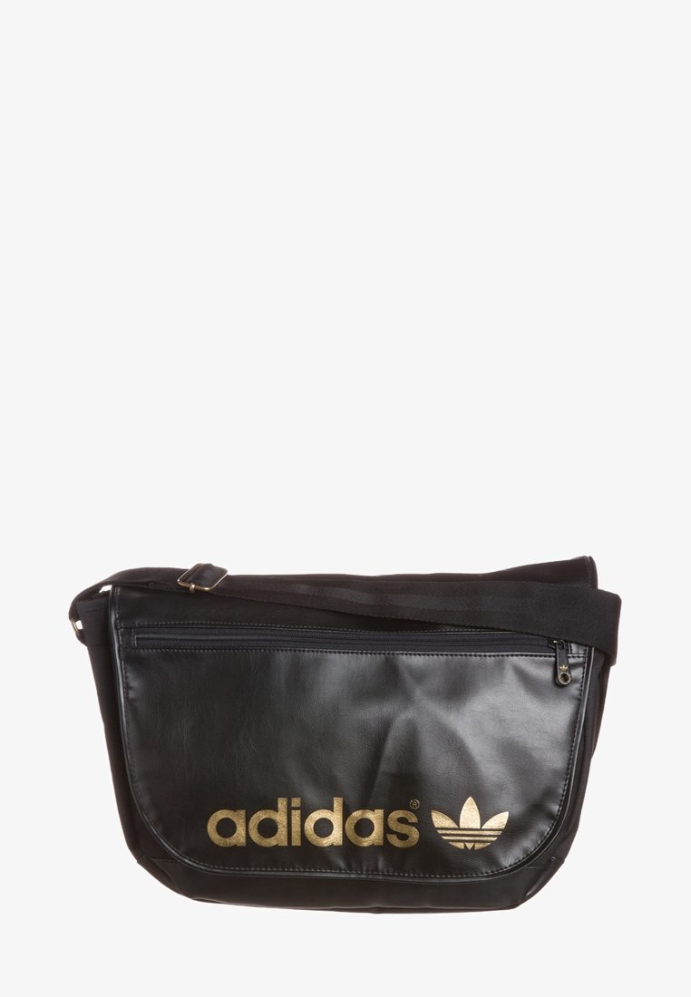 Svart Adidas axelväska med guldlogotyp och justerbar rem, med en framfickan med dragkedja och slät textur.
