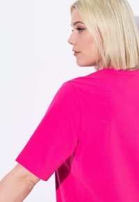 Maglietta a maniche corte rosa brillante con una vestibilità comoda, caratterizzata da un collo rotondo e un tessuto di cotone liscio e morbido.
